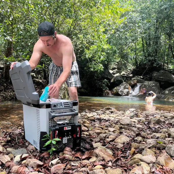 Middle Man running a fridge beside a rainforest creek